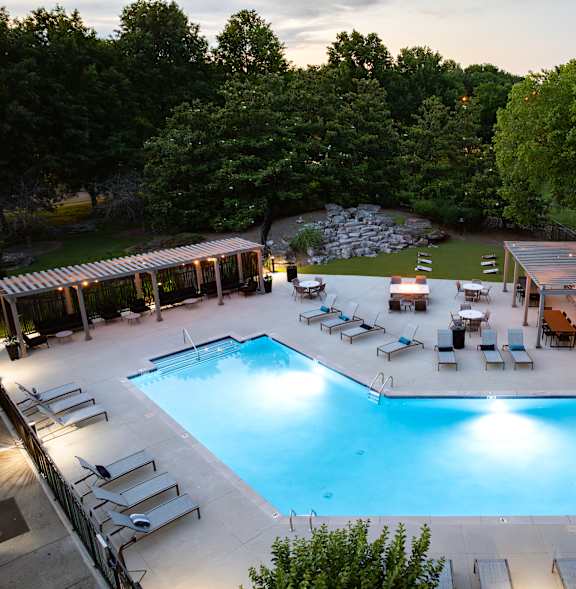 A large outdoor swimming pool surrounded by trees and lounge chairs.