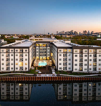 A large white building with a pool in the middle is reflected in the water.