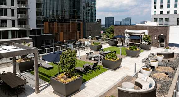 a roof top patio with tables and chairs and grass