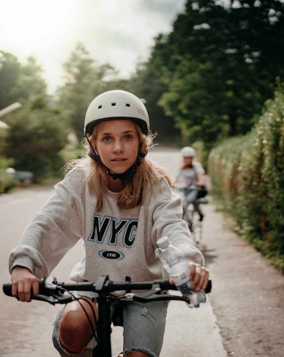 A girl in a helmet is riding a bicycle on a road at Coast Pine