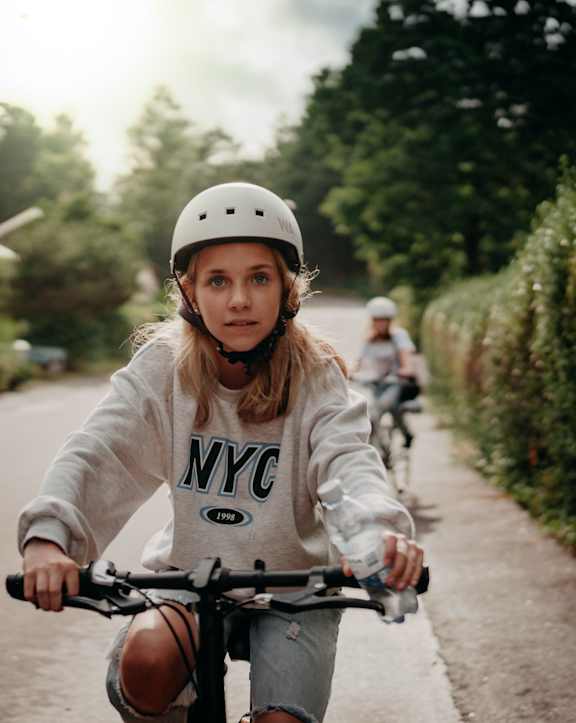 A girl in a helmet is riding a bicycle on a road.