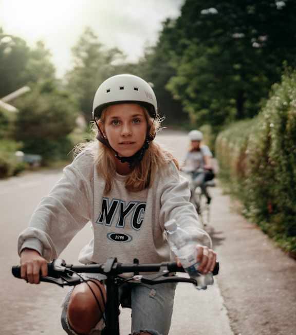 A girl in a helmet is riding a bicycle on a road.