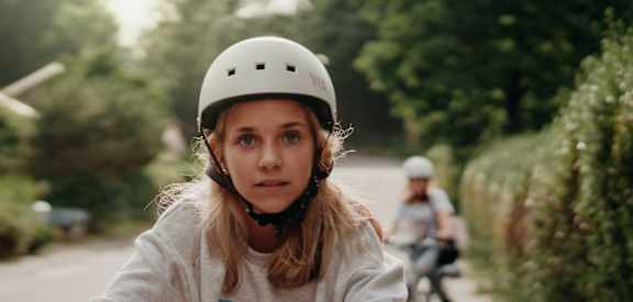 A girl in a helmet is riding a bicycle on a road.