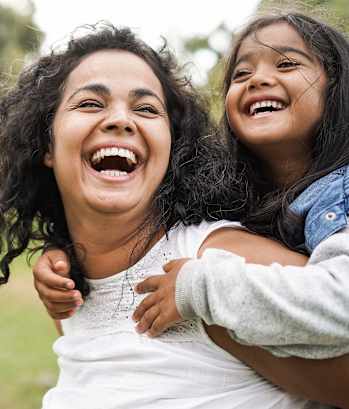a mother and daughter laughing in a park