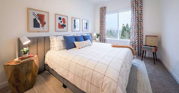 A bedroom with a large bed and a window with curtains.