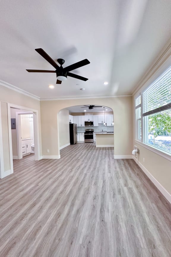 a living room with a ceiling fan and large windows