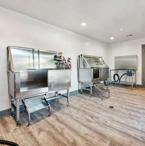 three refrigerators in a room with a wood floor and a door at The Courtyards of Chanticleer, Virginia Beach, VA