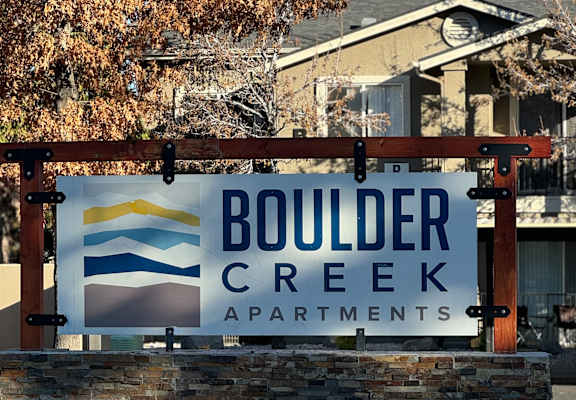 A sign for Boulder Creek Apartments is displayed in front of a building.