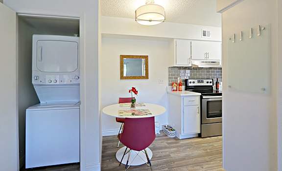 a kitchen with a washer and dryer and a table and a laundry room at Spring Meadow Apartments, Glendale, AZ