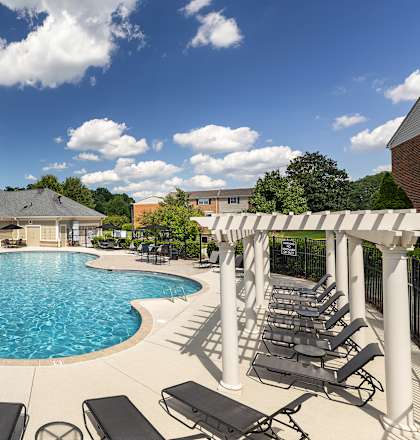 A large outdoor swimming pool surrounded by sun loungers and a covered seating area.