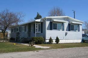 A white house with a porch and a tree on the roof.