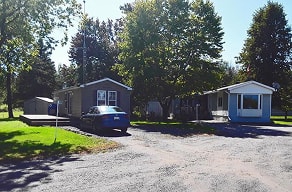 A gravel area in front of a house with a car parked in front of it.