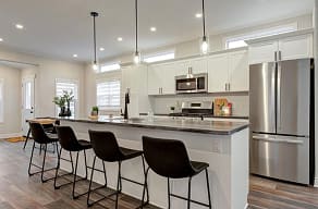 A kitchen with a white counter top and a stainless steel refrigerator.