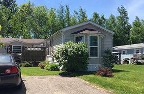 A grey house with a brown roof and a car parked in front.