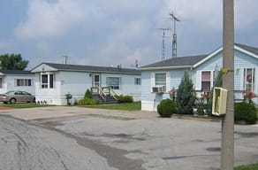 A small blue house with a grey roof and a white car parked in front.