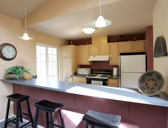 A kitchen with a bar area and a clock on the wall.