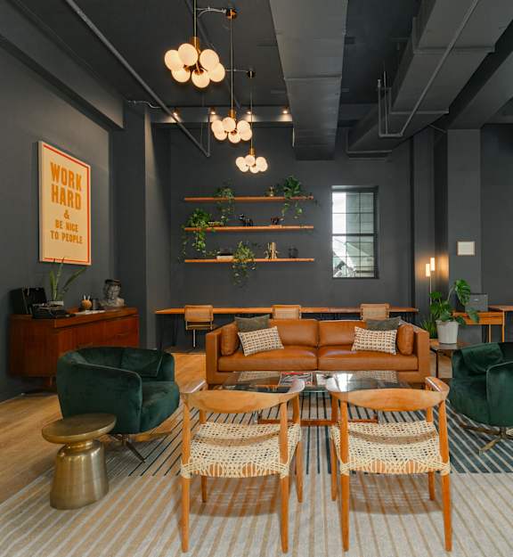 A restaurant with a long table and chairs with a neon sign that says kitchen.