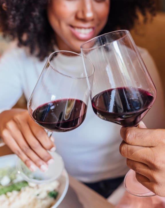 a couple toasting their wine glasses with a meal in front of them