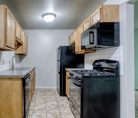 A kitchen with black appliances and wooden cabinets.