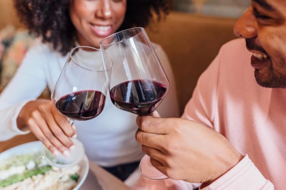 man and woman clinking glass of red wine