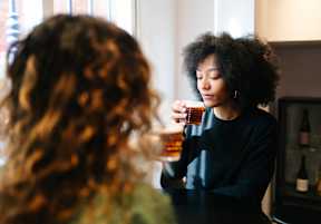 two women sitting at a table with a glass of beer
