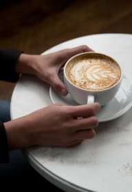 a person holding a cup of coffee on a table at Gage On Sixth, Tacoma