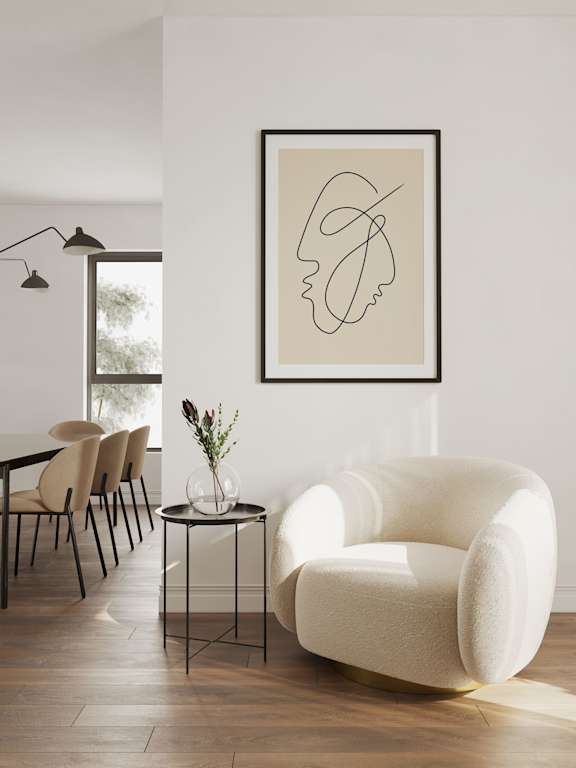 A white chair sits in a room with a framed drawing on the wall.