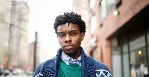 a man wearing a green sweater and a blue jacket on the street