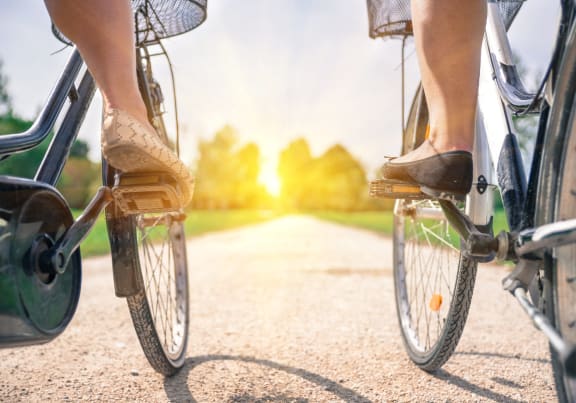 two people riding bikes down a road with the sun in the background at Brighton Oaks, New Brighton, MN 55112