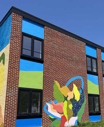 A large mural of a woman with a flower is painted on the side of a brick building.