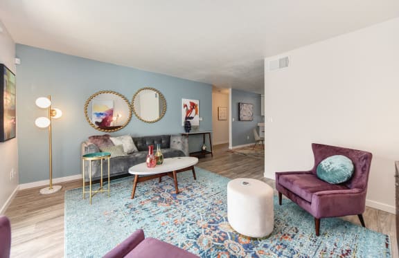 a living room with blue walls and purple furniture and a blue rug at The Legacy Apartments, California, 95843