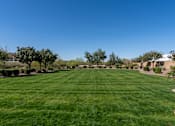 Thumbnail 3 of 5 - A large, well-maintained lawn with a clear blue sky above.