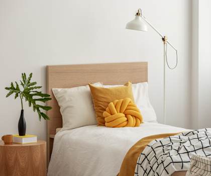 A bed with a white comforter and a yellow pillow is in the image.