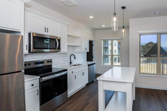 A kitchen with a refrigerator, microwave, and oven.