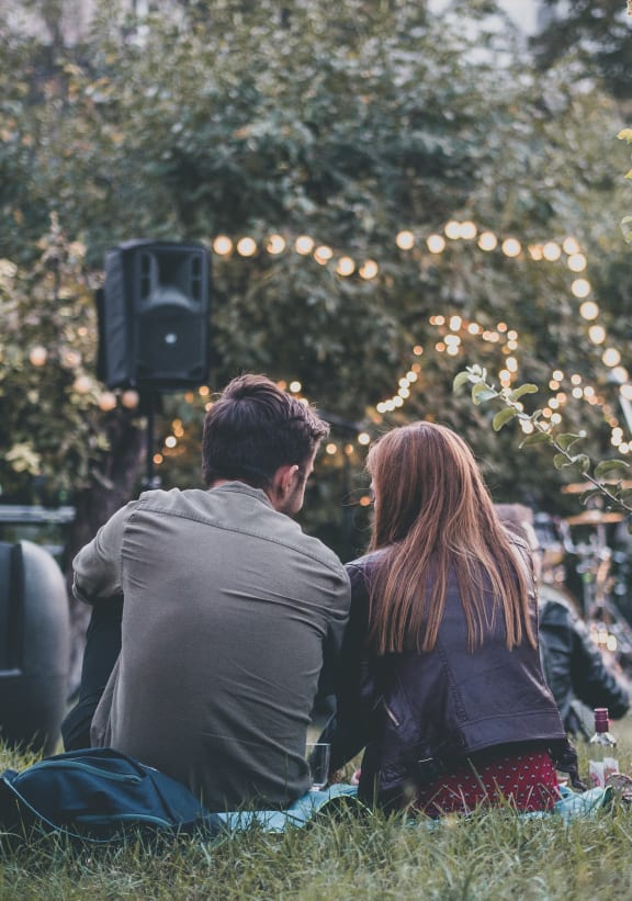 a couple sitting in the grass at an outdoor concert