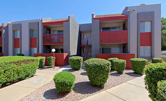 a building with a courtyard and hedges in front of it at Spring Meadow Apartments, Glendale, AZ