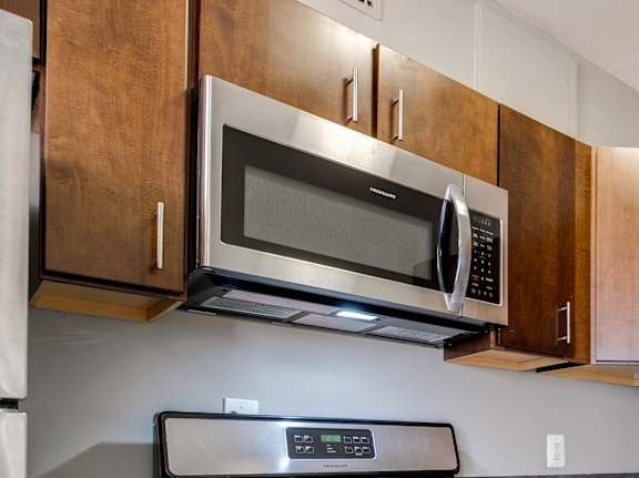 A kitchen with a black stove top oven and a black microwave above it.