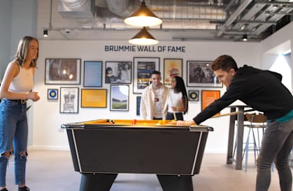 a man plays pool on a table while two women look on