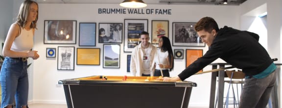 a man plays pool on a table while two women look on