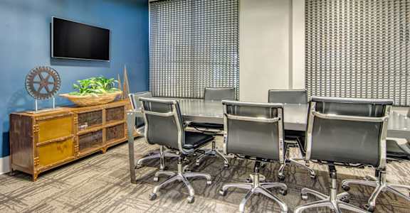 a conference room with a table and chairs and a tv on the wall