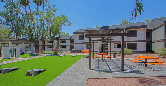 a courtyard with picnic tables and benches at the enclave at woodbridge apartments in sugar land,