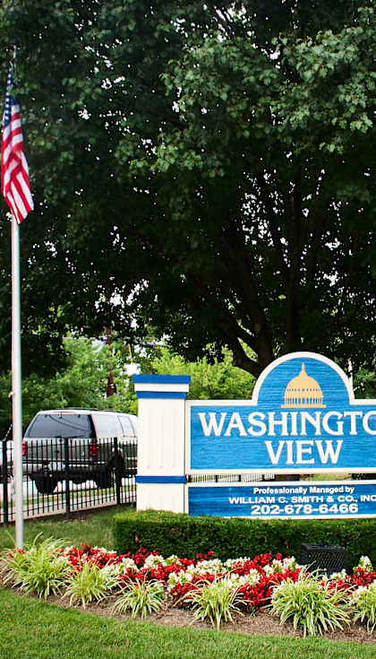 a sign view in front of a building with two flags