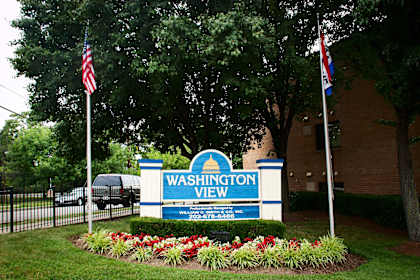 a sign view in front of a building with two flags