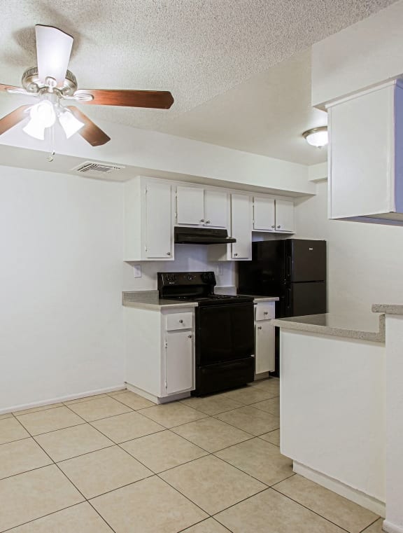 an empty kitchen with a ceiling fan and a sink