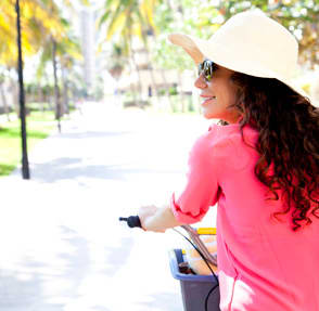 a woman wearing a hat and sunglasses riding a bike