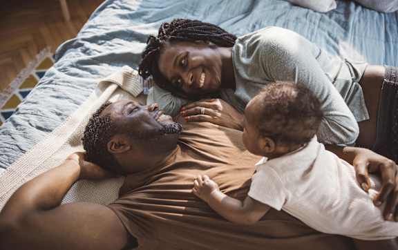 A family of three is lying on a bed.