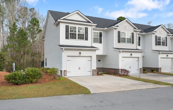 a white house with white garage doors and a driveway