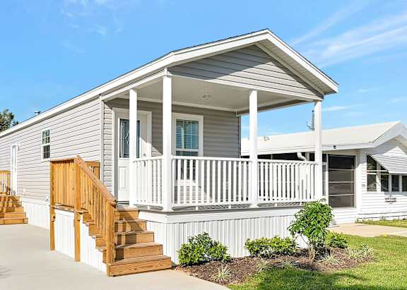 A small house with a porch and a car parked in front.