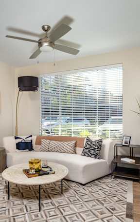 A living room with a white couch, a yellow chair, and a black television.
