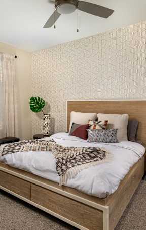 A bedroom with a bed, nightstand, and window with curtains.